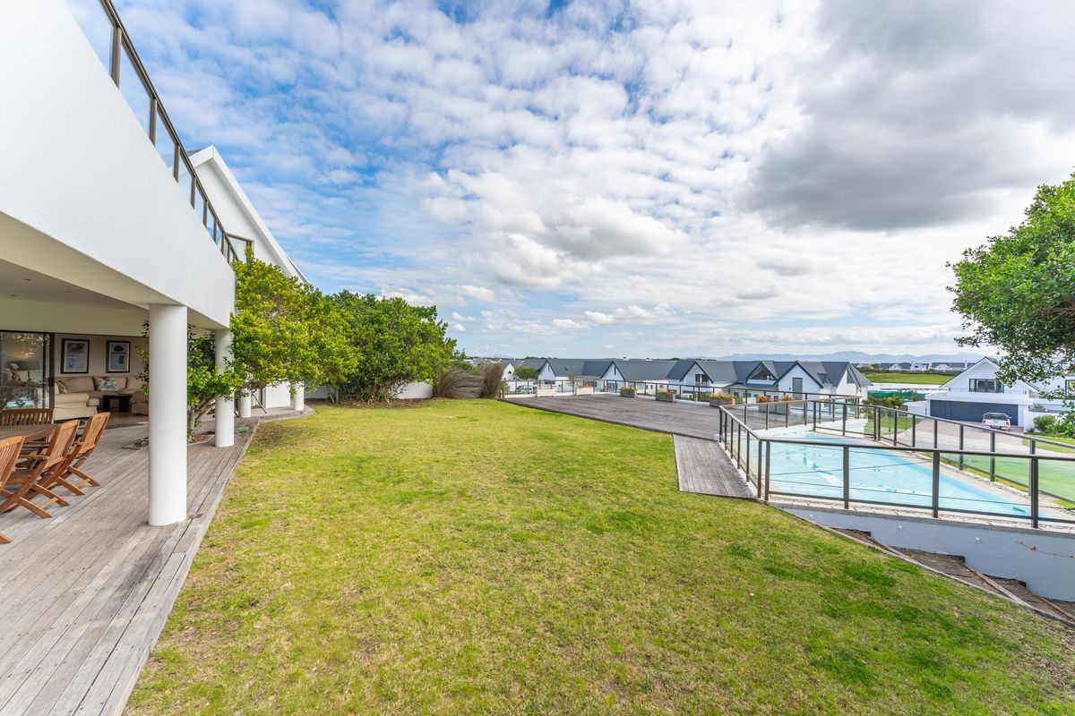 Spacious rear garden featuring a swimming pool, timber decking, and a covered patio area with views of the surrounding estate.