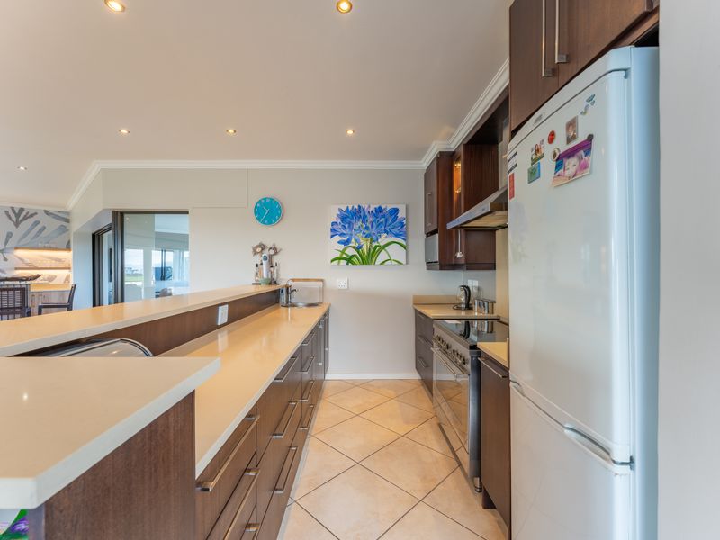 Modern kitchen featuring dark wood cabinetry, stone countertops, stainless steel gas stove, and tiled flooring, seamlessly integrated into an open-plan living space.