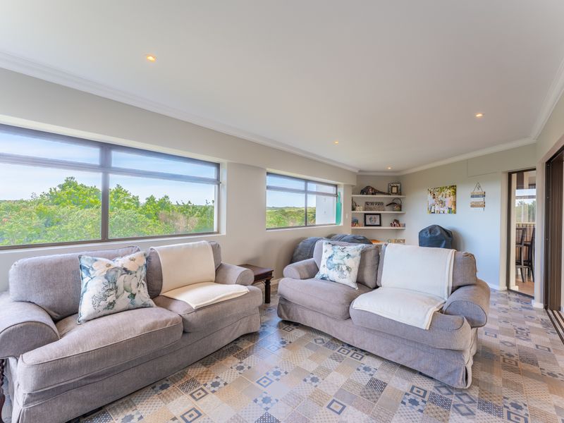 A bright living room featuring patterned ceramic floor tiles, recessed downlights, built-in shelving, and large windows offering natural light and scenic views.