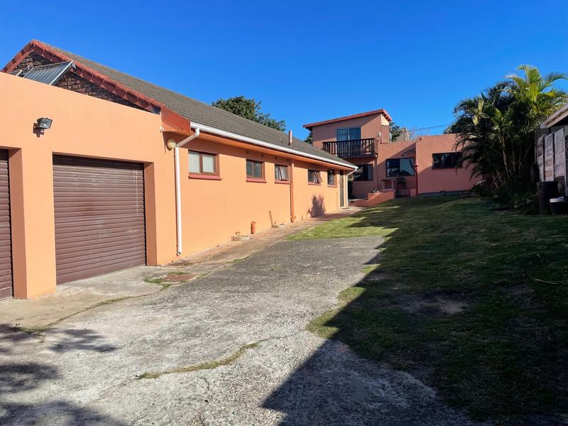 Rear view of the property featuring a concrete driveway, garage access, and a balcony on the upper level.