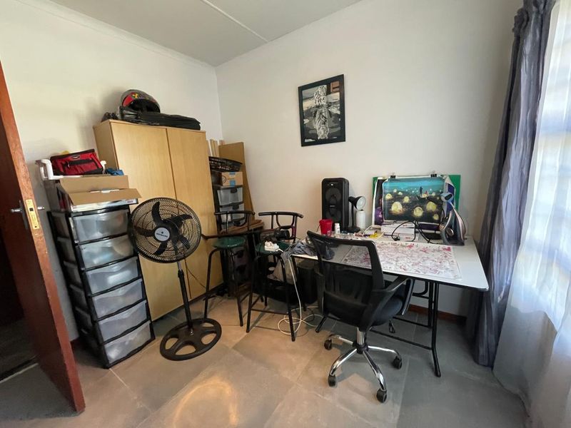 A functional bedroom space featuring tiled flooring and neutral wall finishes, currently utilized as a home office area.