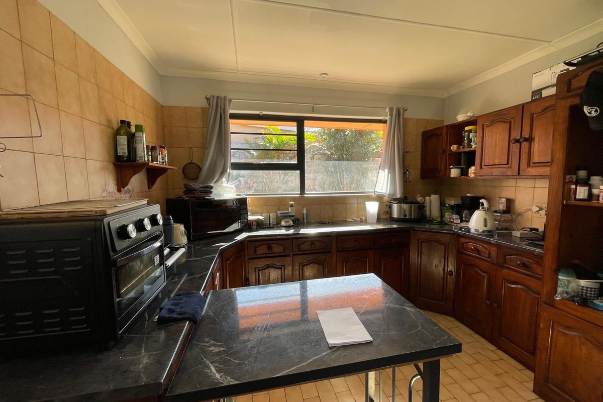 A functional kitchen featuring traditional wooden cabinetry, dark laminate countertops, and tiled backsplash, offering a classic layout with potential for modern updates.