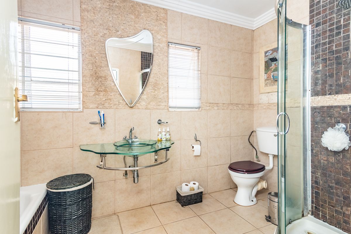 A functional bathroom featuring a glass vessel sink, a separate shower enclosure, and neutral wall tiling throughout.