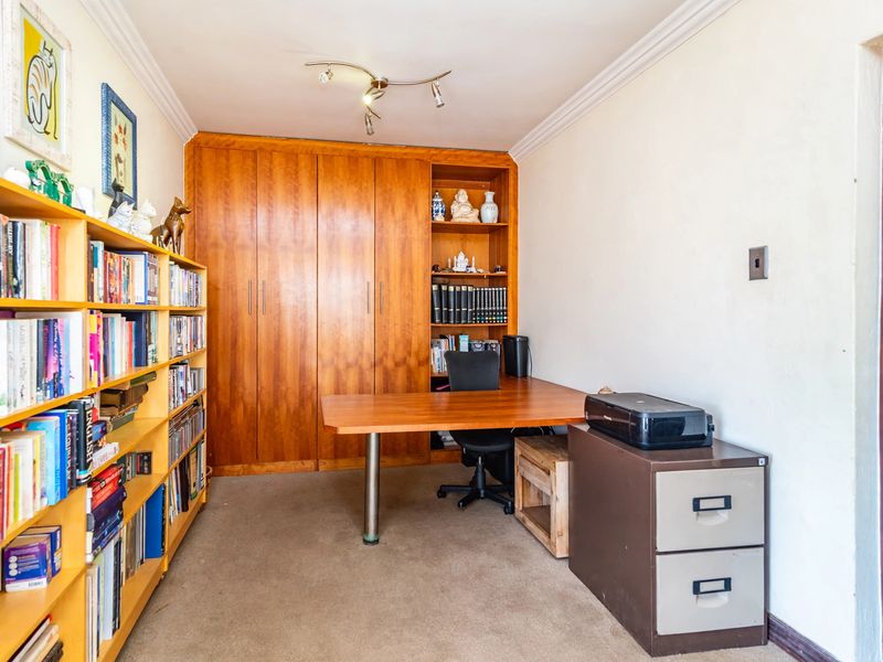A functional home office featuring extensive built-in wooden cabinetry and shelving, providing ample storage and a dedicated workspace.