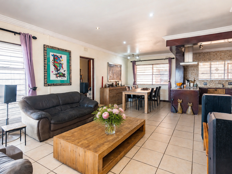 Spacious open-plan living and dining area featuring tiled floors, recessed lighting, and a functional kitchen with a central island and modern extractor fan.