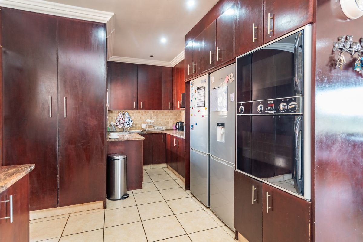 A functional kitchen featuring dark wood cabinetry, granite countertops, tiled flooring, and a built-in double wall oven.