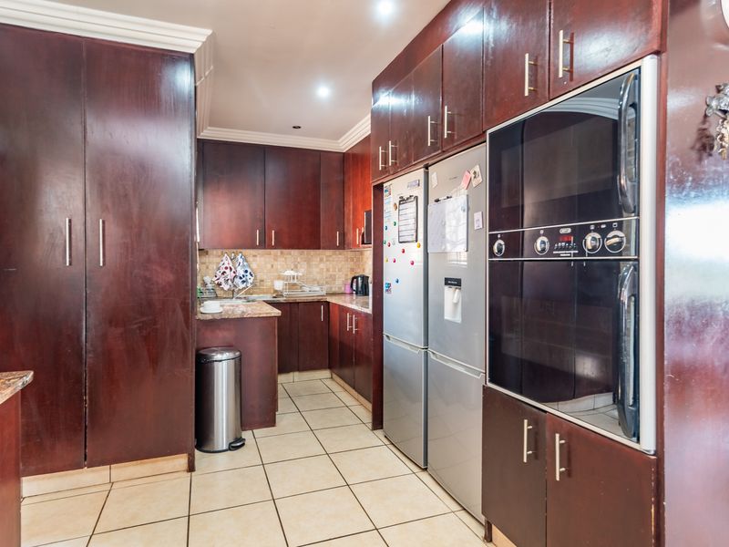 A functional kitchen featuring dark wood cabinetry, granite countertops, tiled flooring, and a built-in double wall oven.