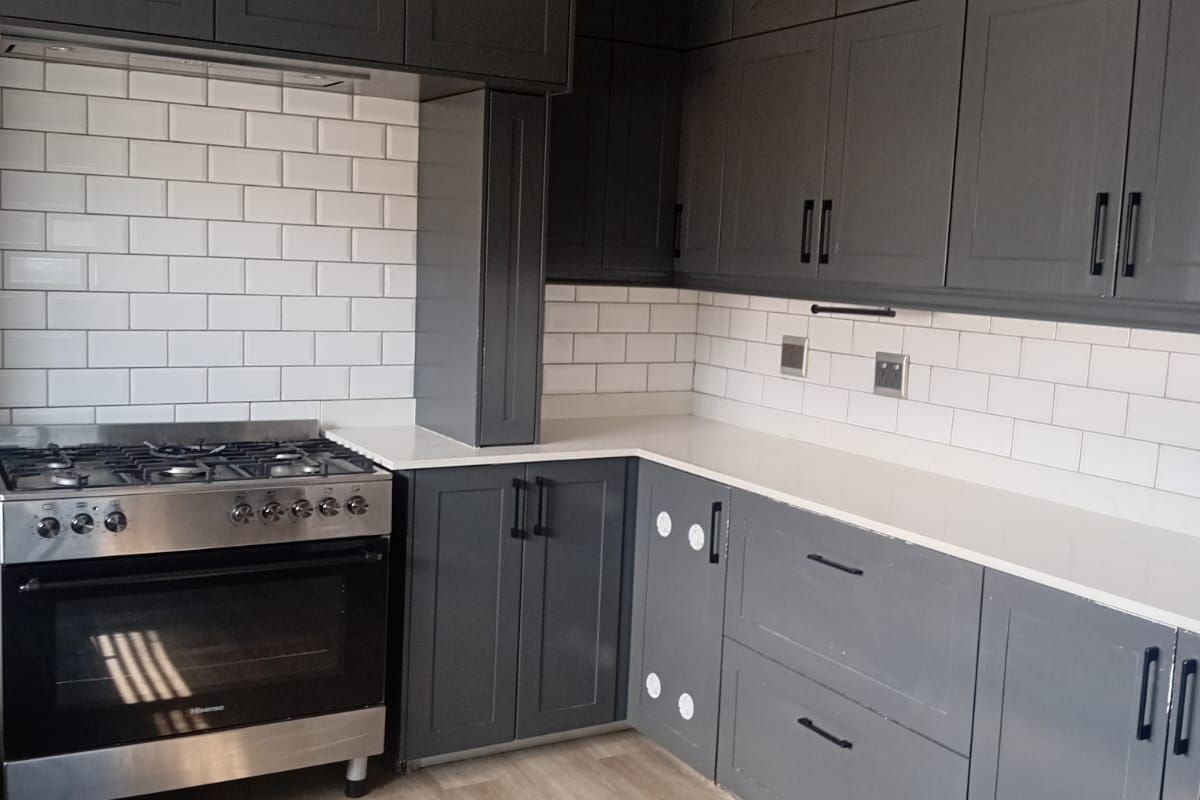 Modern kitchen featuring dark grey cabinetry, white subway tile backsplash, quartz countertops, and a stainless steel gas stove.