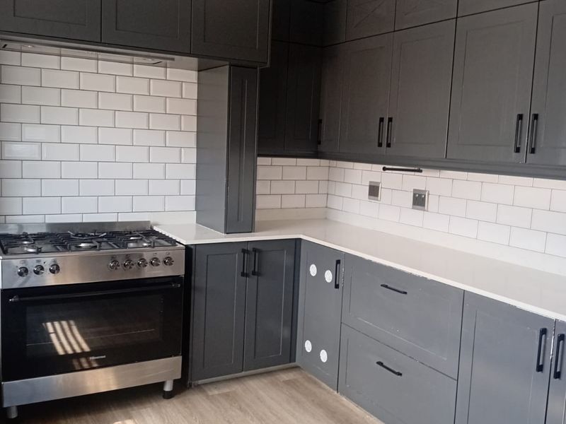 Modern kitchen featuring dark grey cabinetry, white subway tile backsplash, quartz countertops, and a stainless steel gas stove.