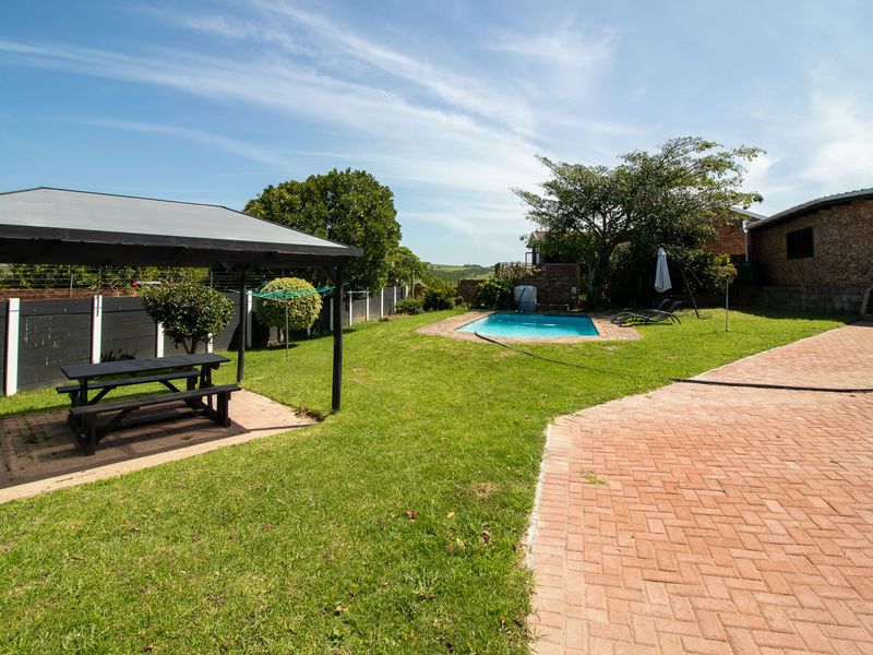 Outdoor entertainment area featuring a swimming pool, paved patio space, and a covered gazebo set within a private garden.