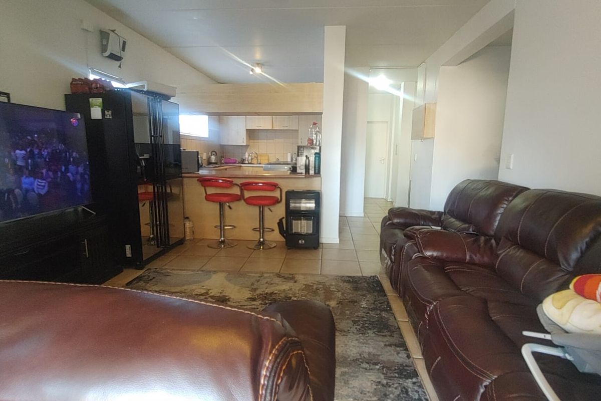 Open-plan living area featuring a kitchen with breakfast bar and tiled flooring, connecting seamlessly to the lounge space.
