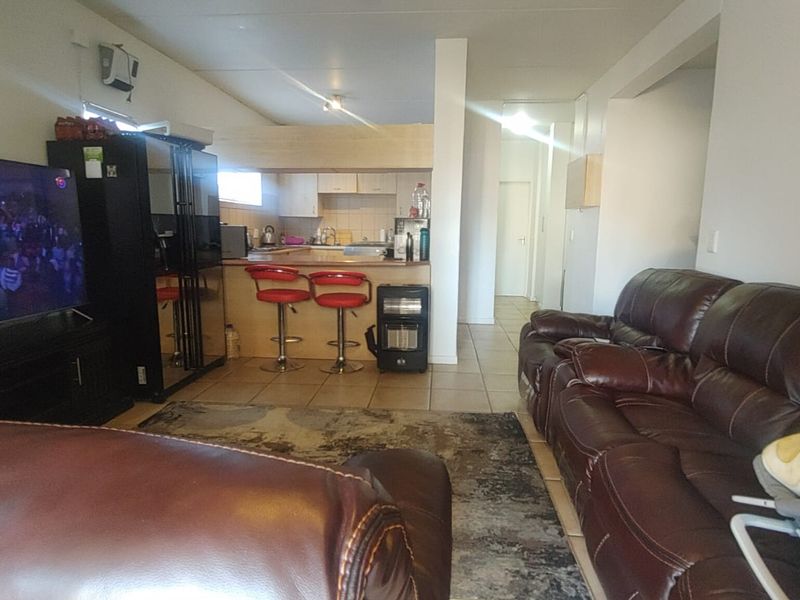Open-plan living area featuring a kitchen with breakfast bar and tiled flooring, connecting seamlessly to the lounge space.