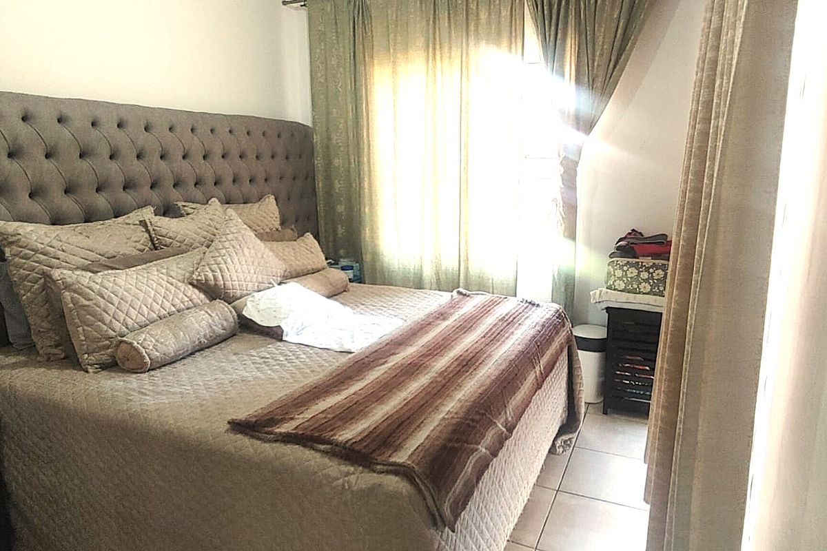 A bedroom featuring tiled flooring and window treatments, with natural light entering through the window.