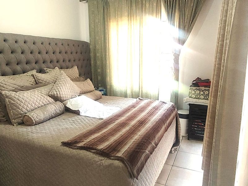 A bedroom featuring tiled flooring and window treatments, with natural light entering through the window.