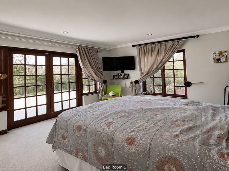 Spacious bedroom featuring carpeted flooring, recessed downlights, and timber-framed glass doors providing direct access to an outdoor balcony area.