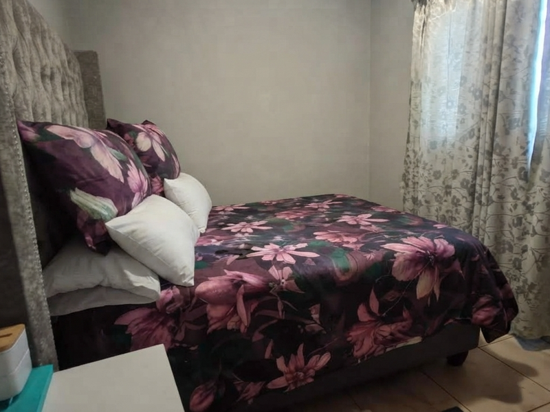 A bedroom featuring tiled flooring and neutral wall finishes, providing a functional space for rest.