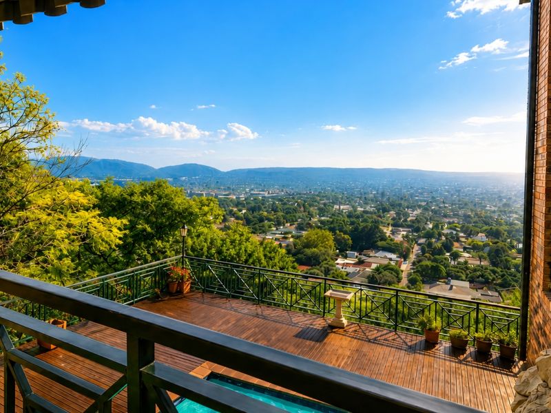 Spacious elevated timber deck balcony featuring a metal balustrade and expansive panoramic views over the surrounding valley and cityscape.