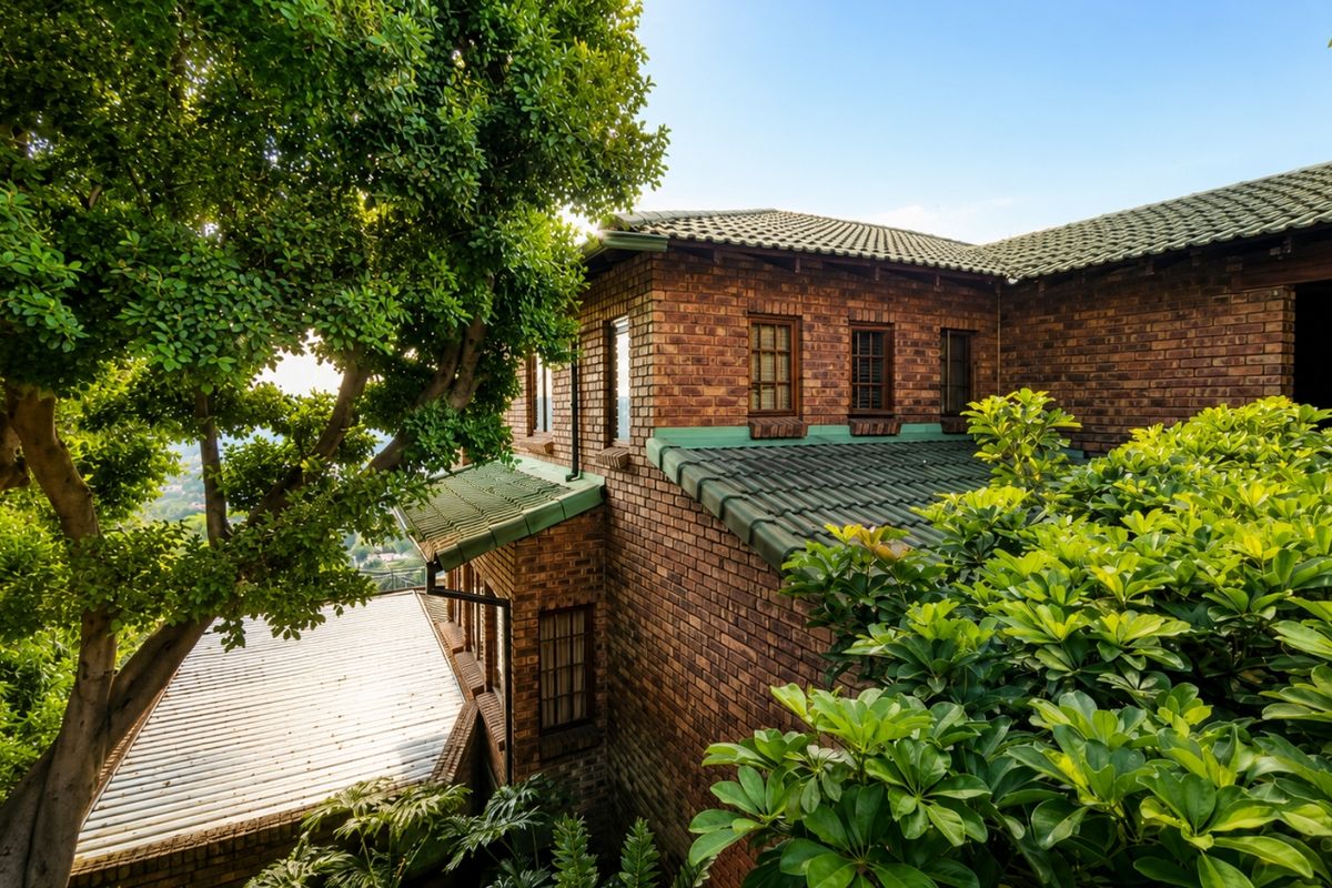 A view of the rear elevation featuring classic face brick construction, green tiled roofing, and established surrounding greenery.
