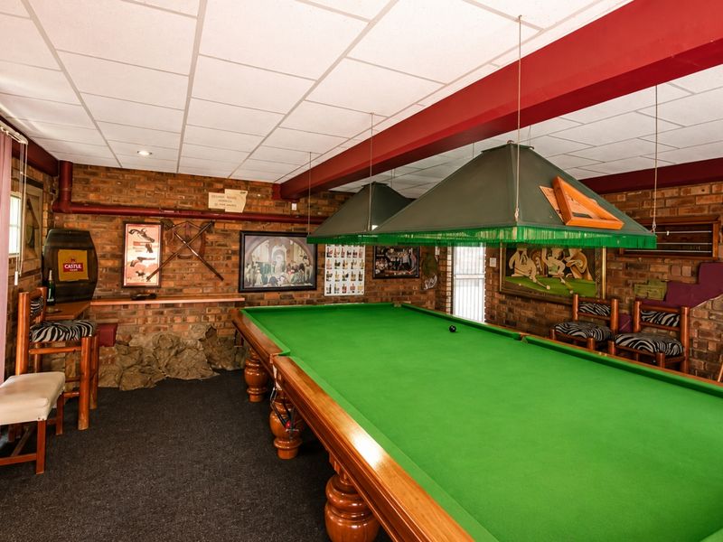 A dedicated entertainment room featuring exposed brick walls, a suspended ceiling, and professional billiard table lighting.