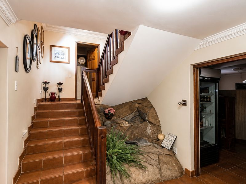 A tiled staircase hallway featuring a wooden balustrade and a unique decorative rock feature built into the stairwell base.