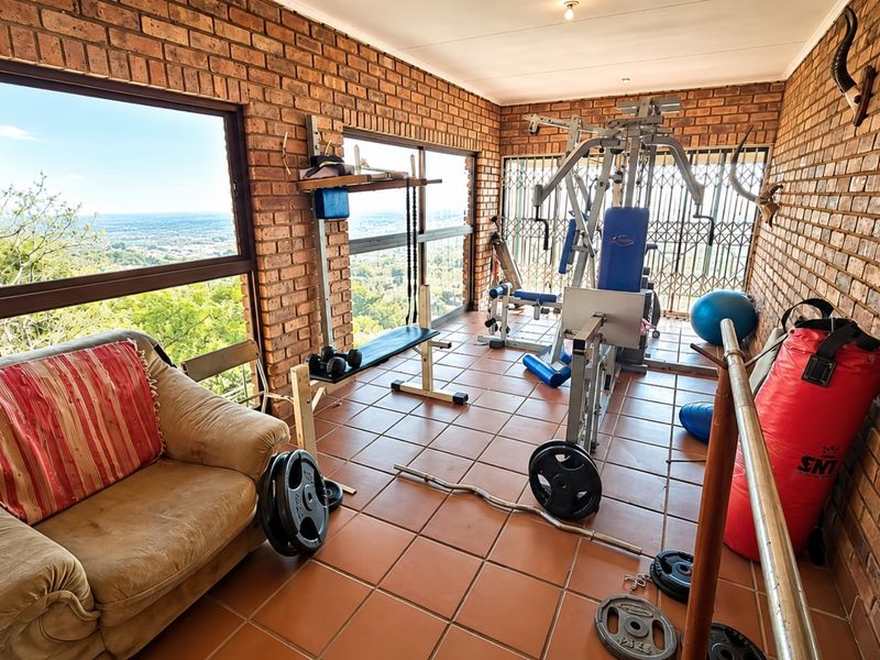 A dedicated gym space featuring exposed brick walls, tiled flooring, and large windows offering expansive elevated views.