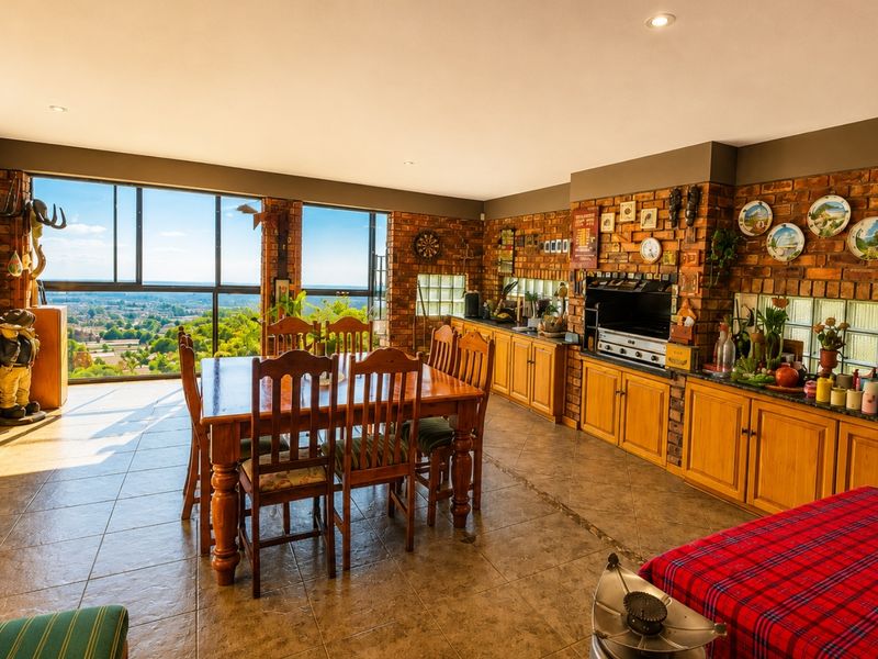 Spacious open-plan living and dining area featuring exposed brick walls, tiled floors, and expansive windows offering panoramic views.