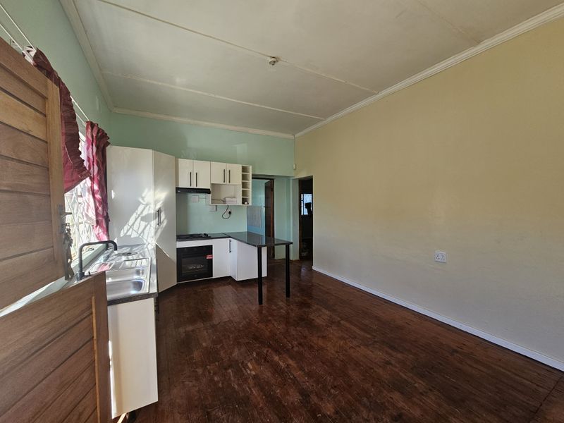 Open plan kitchen and living area featuring built-in cabinetry, integrated oven, hob, and wooden flooring.