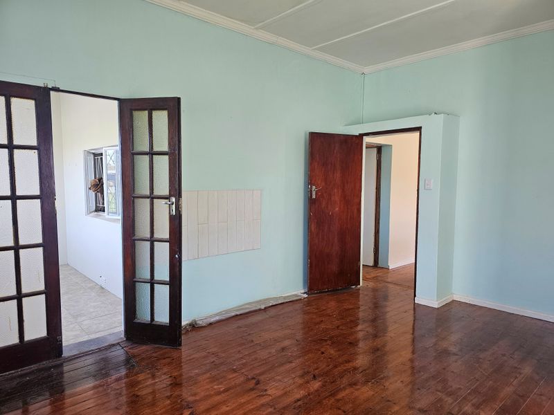 An empty living room featuring polished timber flooring, classic french doors, and neutral wall paint, offering a blank canvas for interior design.