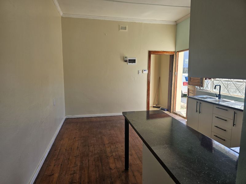 Open plan kitchen and living area featuring timber flooring, built-in cabinetry, and direct access to the exterior.