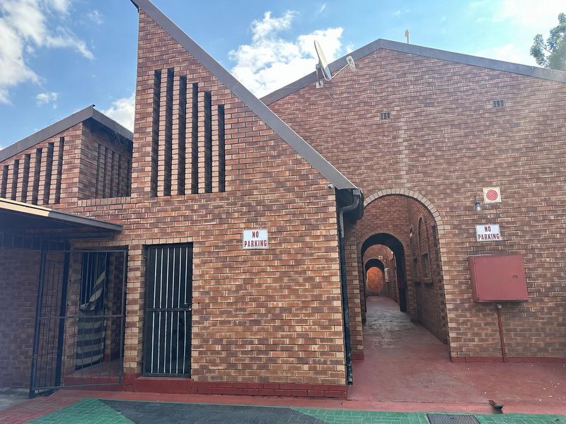 Exterior view of an apartment complex featuring face brick architecture, arched walkways, and secure access points.