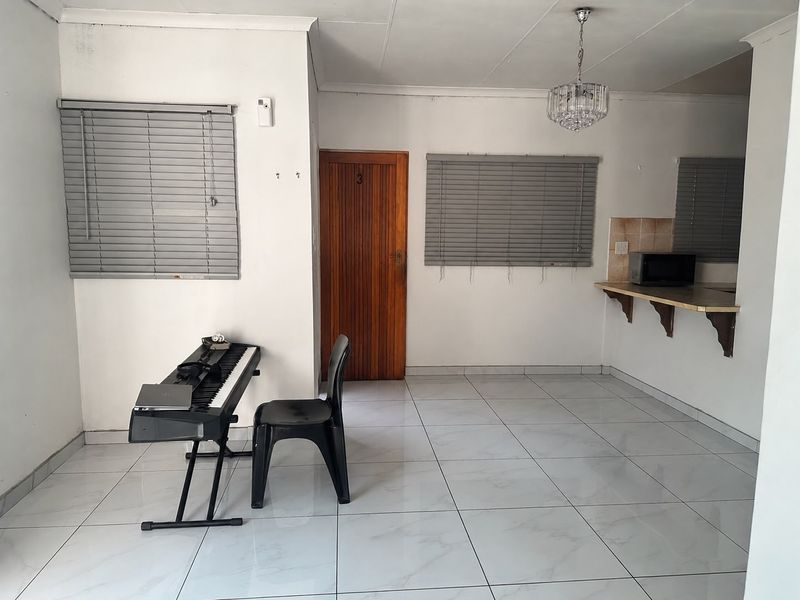 Open plan living area featuring tiled flooring, venetian blinds, and a breakfast counter, offering a functional space for dining and relaxation.