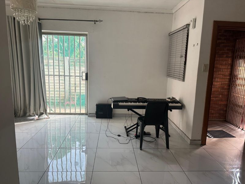 A living area featuring polished marble-look floor tiles, a sliding glass door with security gate, and neutral wall finishes.