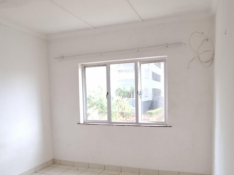 An empty bedroom featuring tiled flooring, an aluminium window, and basic ceiling finishes, providing a blank canvas for renovation or interior design.