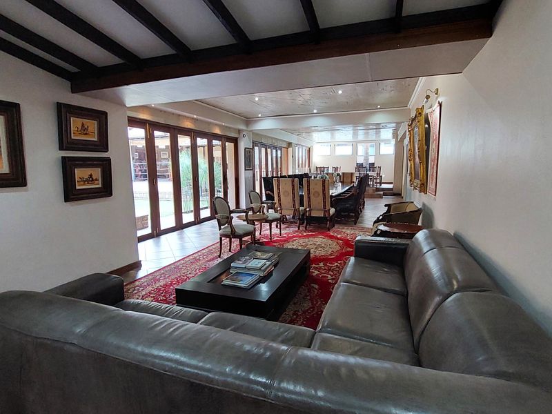 Spacious open-plan living and dining area featuring exposed timber ceiling beams, tiled flooring, and large bi-fold glass doors providing seamless access to the outdoors.