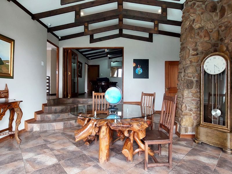 Dining area featuring exposed timber ceiling beams, a prominent stone feature wall, and tiled flooring with a stepped transition to the adjacent room.