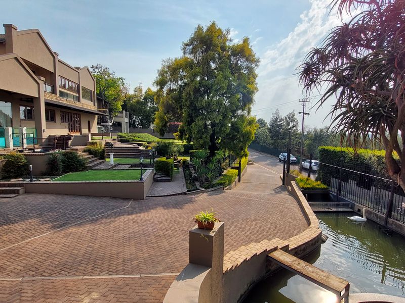 Spacious front exterior featuring a paved driveway, tiered landscaped gardens, retaining walls, and a decorative water feature leading to the main entrance.