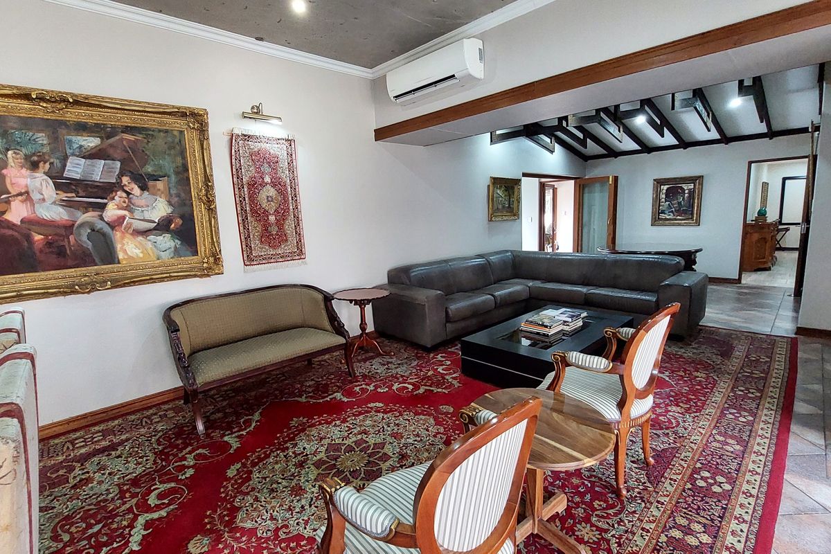 Spacious living room featuring exposed timber ceiling beams, tiled flooring, and a wall-mounted split-system air conditioner.