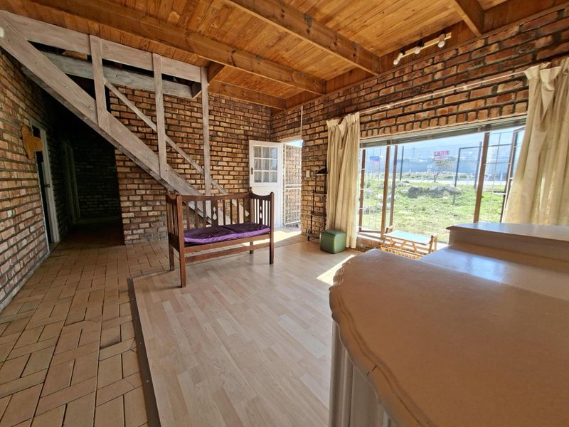 Living area featuring exposed brick walls, timber beam ceilings, and a wooden staircase, with large sliding doors providing natural light and garden access.