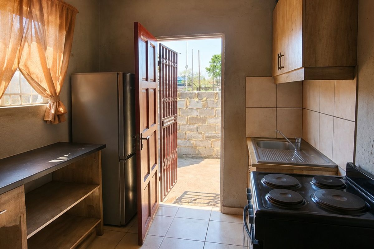 Compact kitchen featuring basic cabinetry, a stainless steel sink, tiled backsplash, and an electric stove, with direct access to an outdoor area.