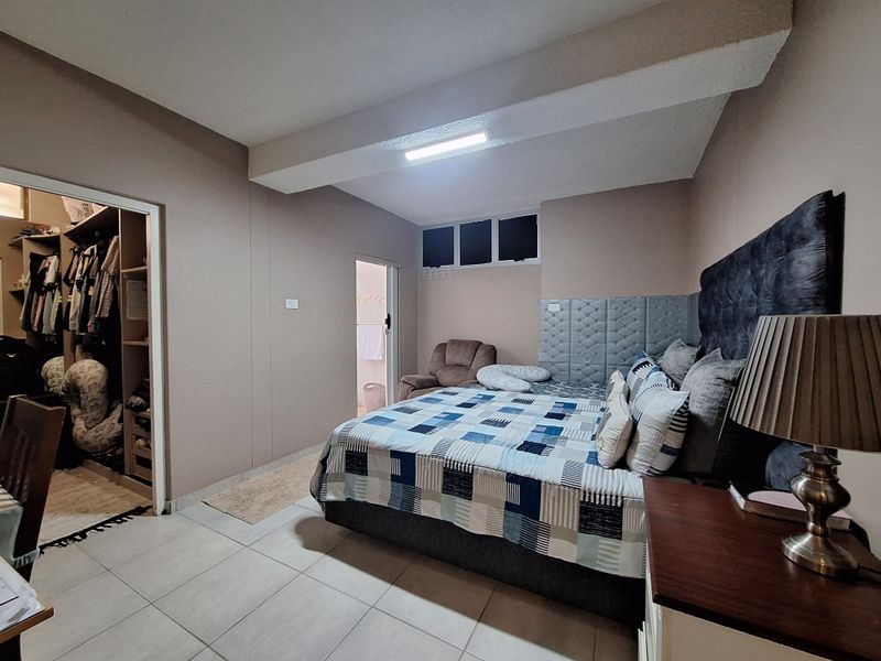 Spacious bedroom featuring tiled flooring, a built-in walk-in closet, and direct access to an en-suite bathroom.