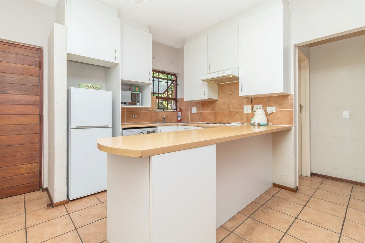 Functional kitchen featuring white built-in cabinetry, a breakfast bar, tiled backsplash, and ceramic floor tiles.