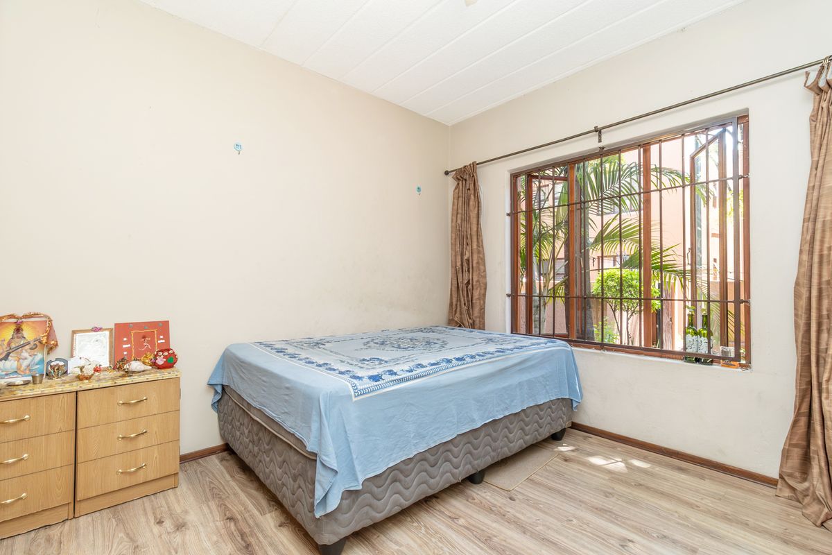 A bedroom featuring laminate flooring and a window with security bars. The space requires cosmetic updates to the walls and ceiling.