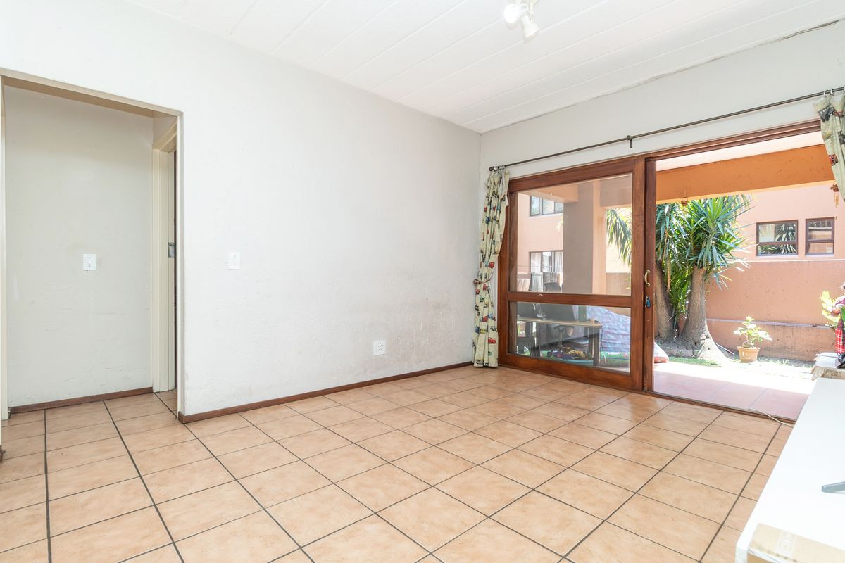 An empty living room featuring tiled flooring and a large sliding glass door providing access to an outdoor patio area.
