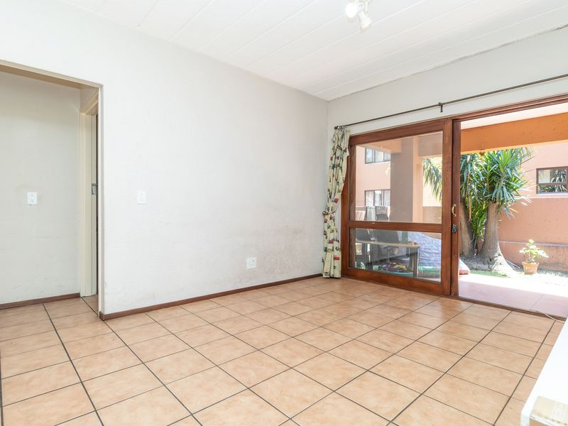 An empty living room featuring tiled flooring and a large sliding glass door providing access to an outdoor patio area.