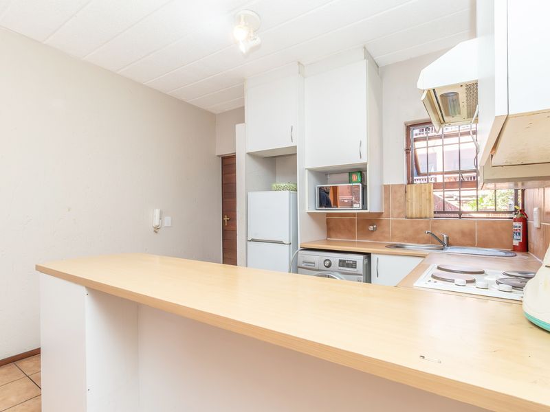 Functional kitchen featuring built-in cabinetry, laminate countertops, a tiled backsplash, and an integrated electric hob with extractor fan.