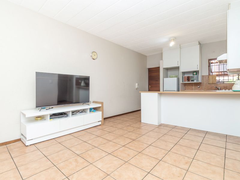 Open plan living area featuring tiled flooring and a functional kitchen with built-in cabinetry, breakfast bar, and tiled backsplash.