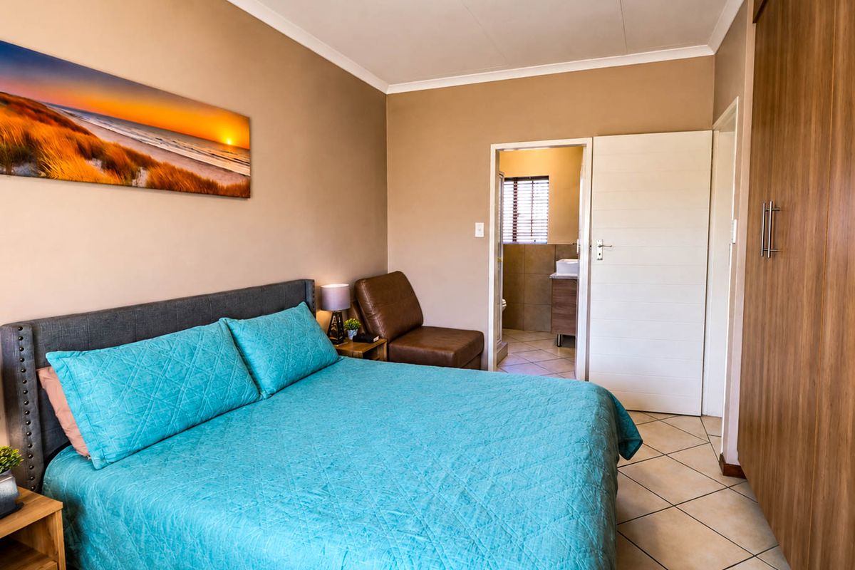 A well-maintained bedroom featuring tiled flooring, a built-in wardrobe, and direct access to an en-suite bathroom.
