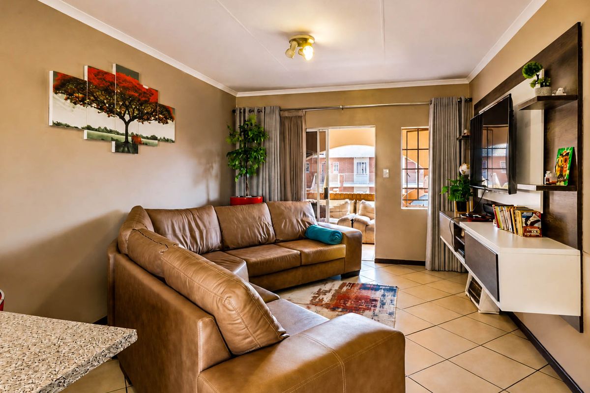 A comfortable living room featuring tiled flooring, a built-in media console, and a sliding glass door providing access to the outdoor patio area.