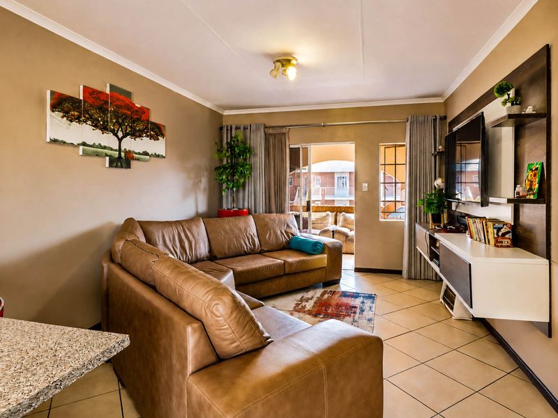 A comfortable living room featuring tiled flooring, a built-in media console, and a sliding glass door providing access to the outdoor patio area.