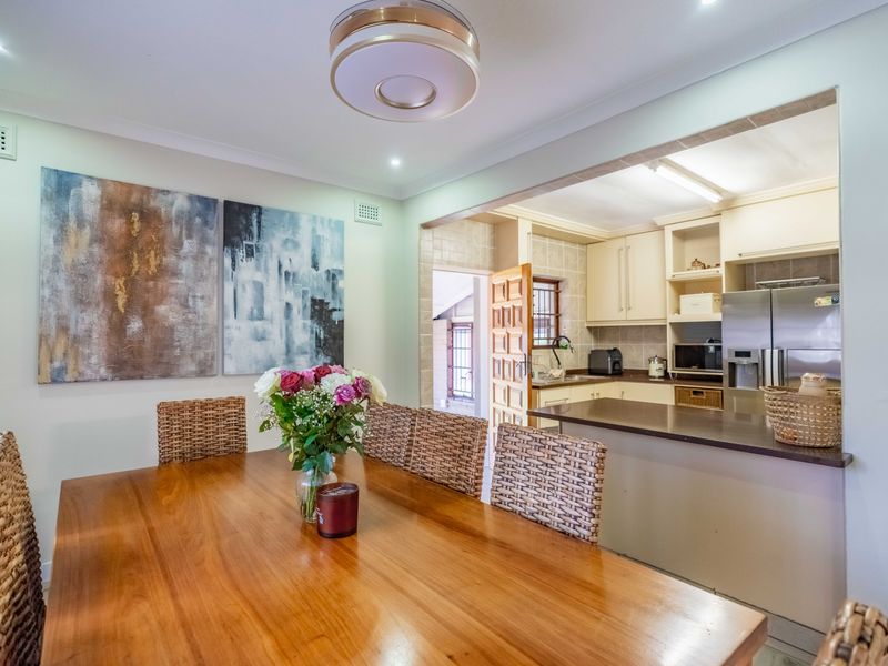 Open plan dining area adjacent to a functional kitchen featuring built-in cabinetry, a breakfast bar, and neutral finishes.
